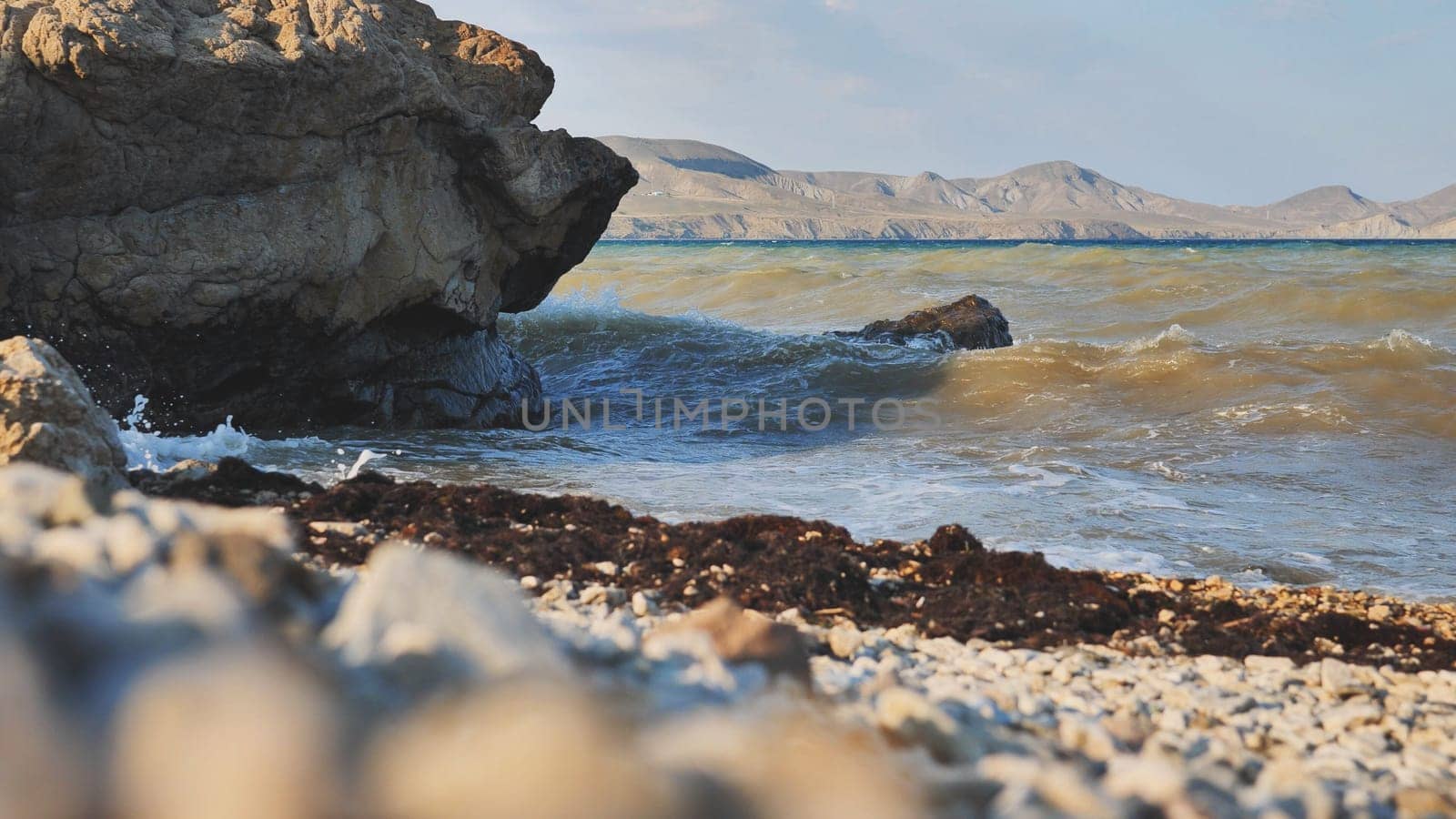 Scenic view of waves crashing on a rocky beach in Crimea, with mountains visible in the distance