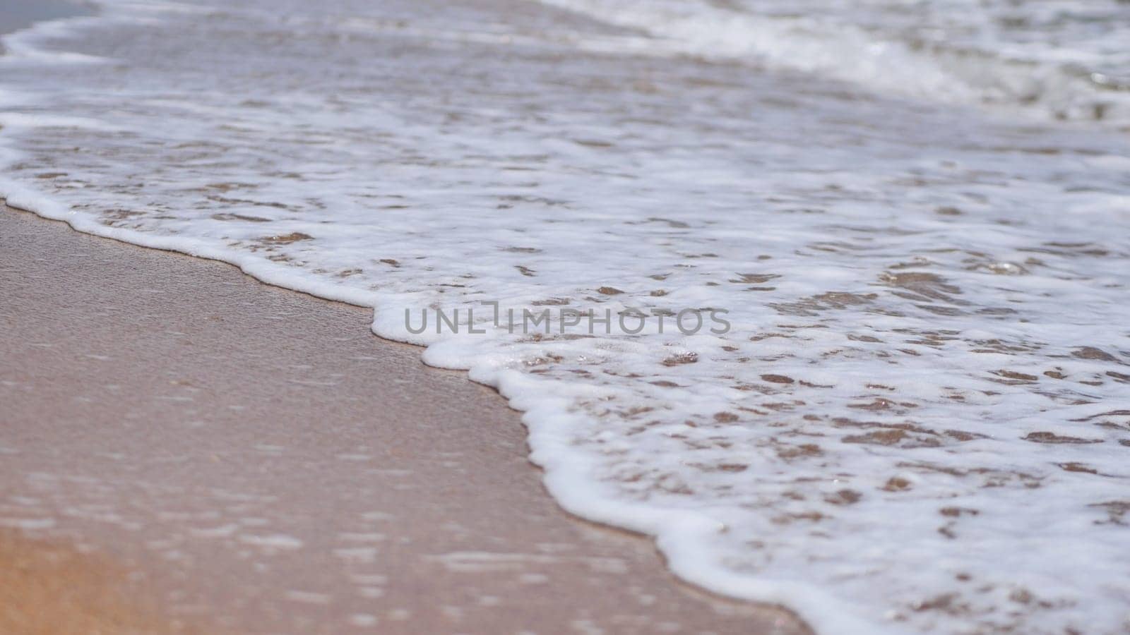 Gentle waves washing over sandy beach, creating a tranquil and serene coastal scene