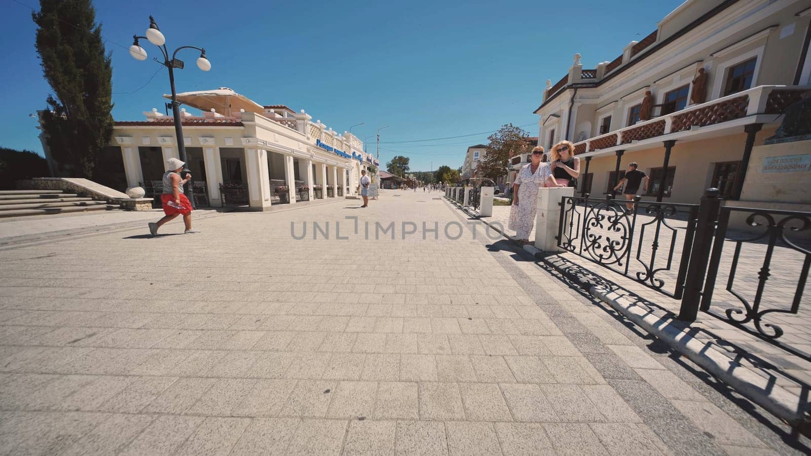 People enjoying a walk along the paved promenade in Gurzuf, Crimea, on a sunny summer day