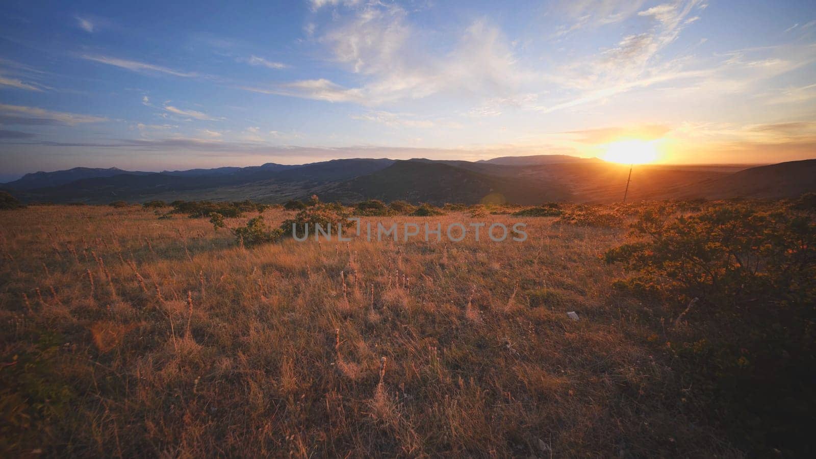 Golden hour illuminating Crimean landscape with dry meadow in the foreground and layers of mountains in the background