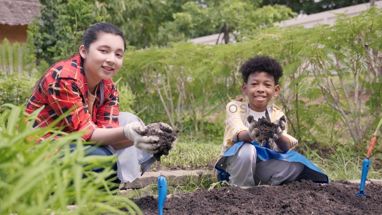 Happy children group girl and boy of diverse learning environment for plants vegetable at garden farm they holding black soil on hands, Ecology, agriculture school learning