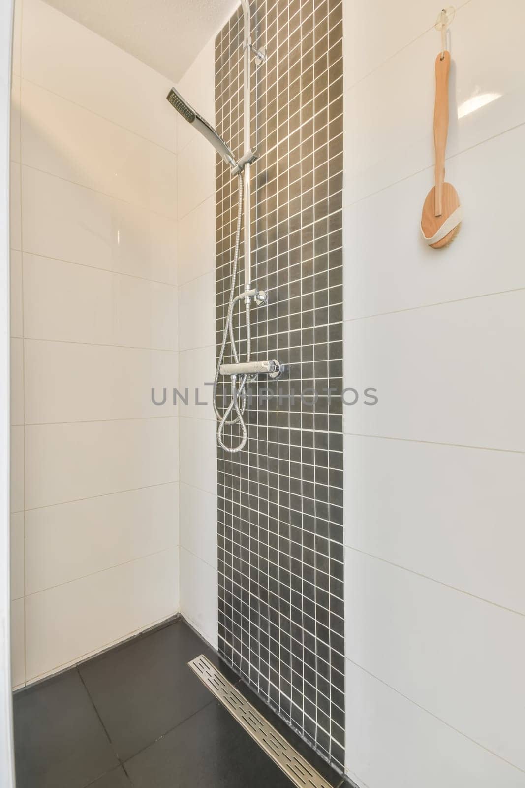 a bathroom with black and white tiles on the walls, along with a shower head in the floor is tiled