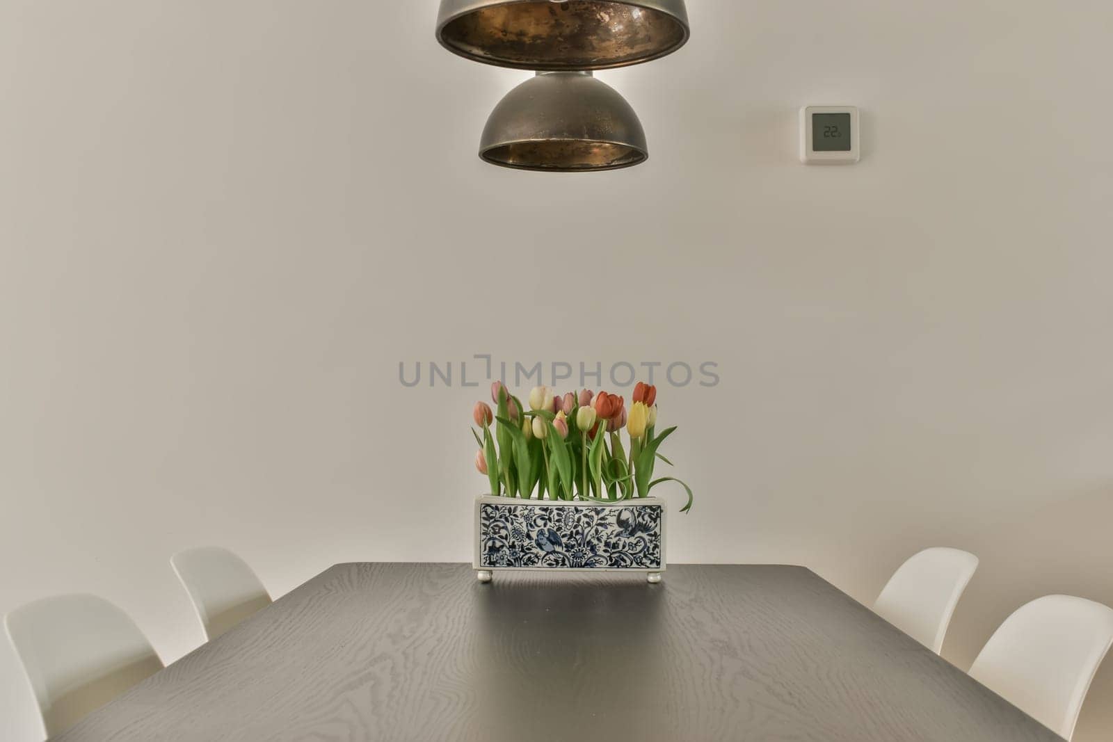 a dining room with white chairs and a wooden table in front of a large pendant light hanging above the table