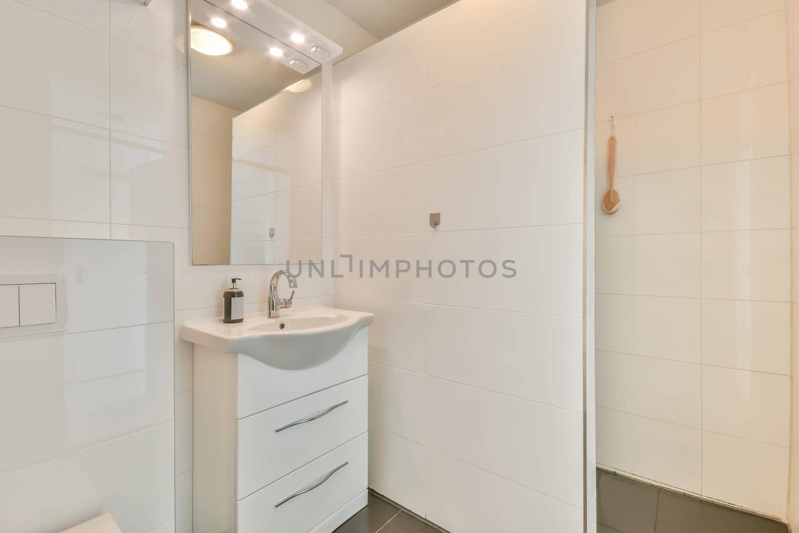 a bathroom with white walls and tile flooring, including a sink in the corner between the shower stall door