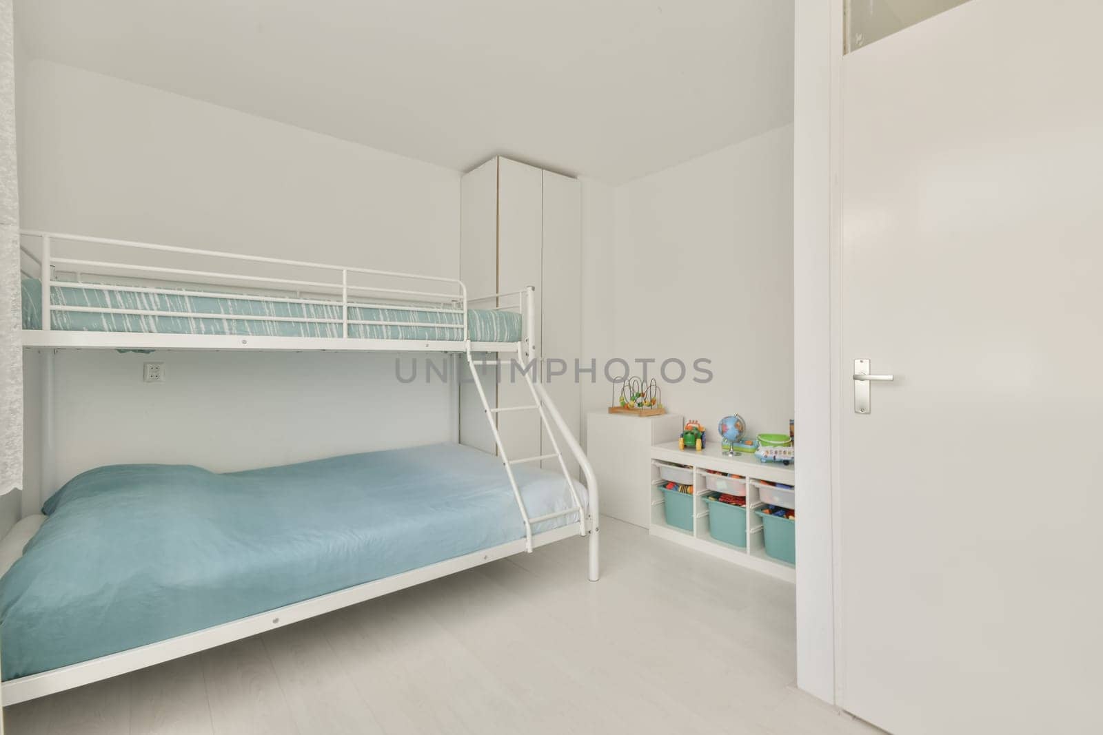 a children's room with bunks and storage space in the wall is white, there is a blue blanket on the bed