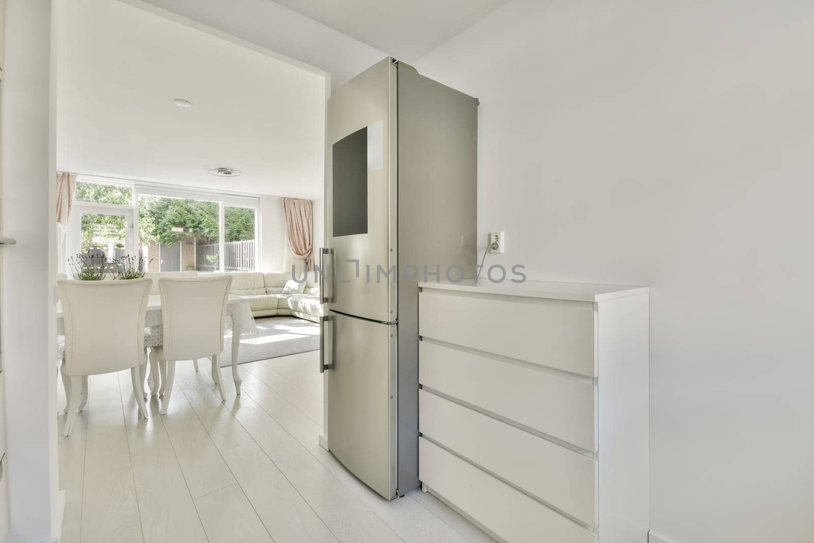 a kitchen and dining area in a modern apartment with white walls, wood flooring and an open door leading to the living room