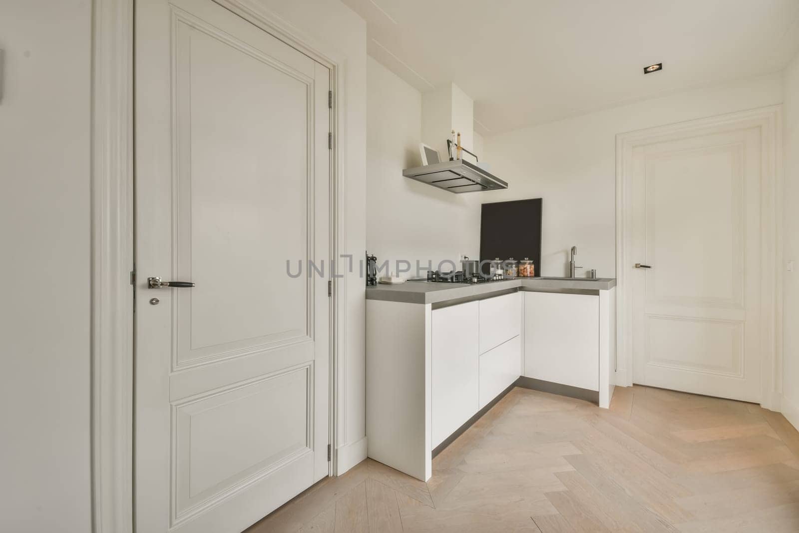a kitchen with white cabinets and black appliances on the wall above it is an open door that leads to another room