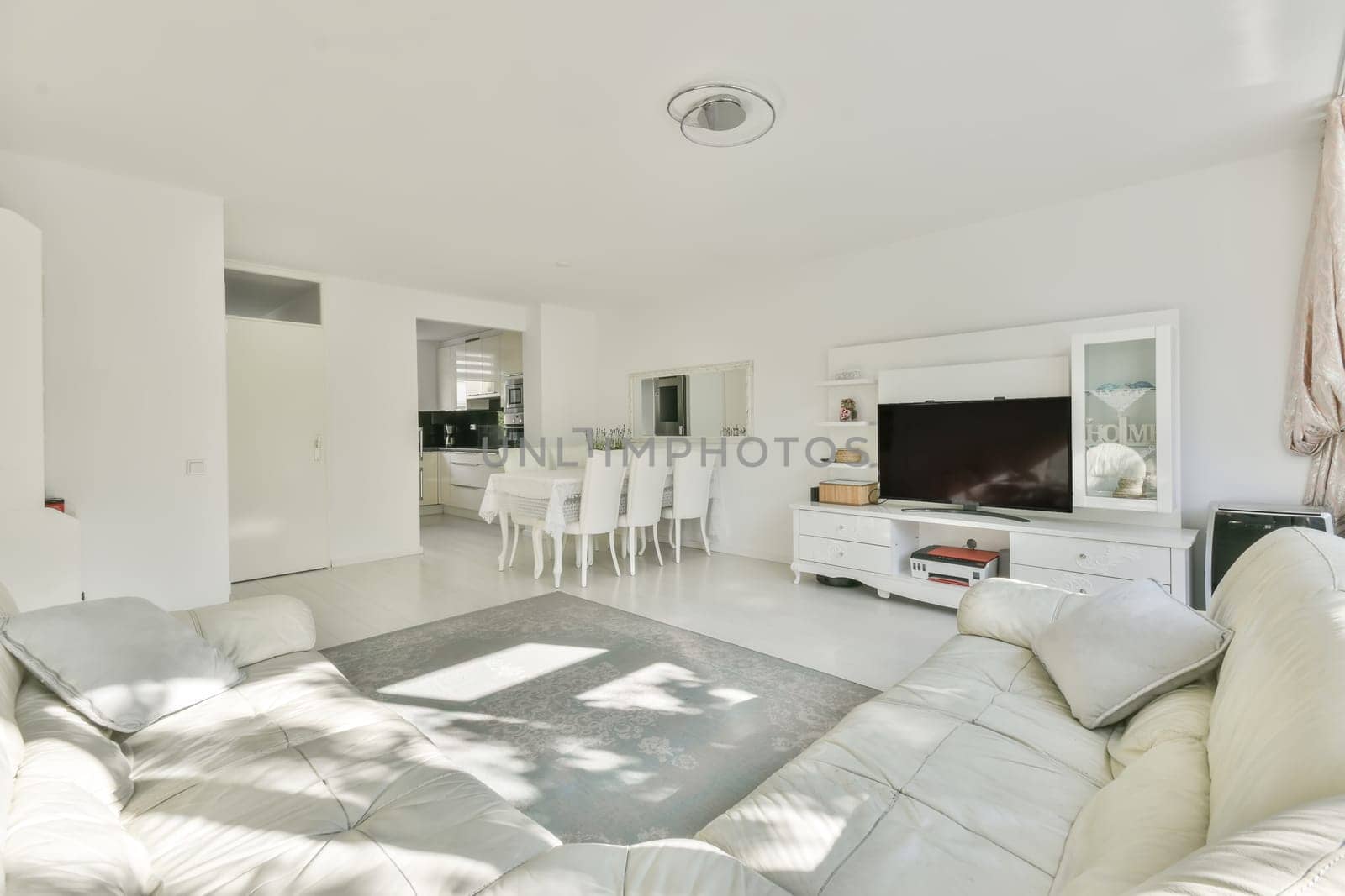 a living room with white couches and television on the wall in front of the sofa is an entertainment center