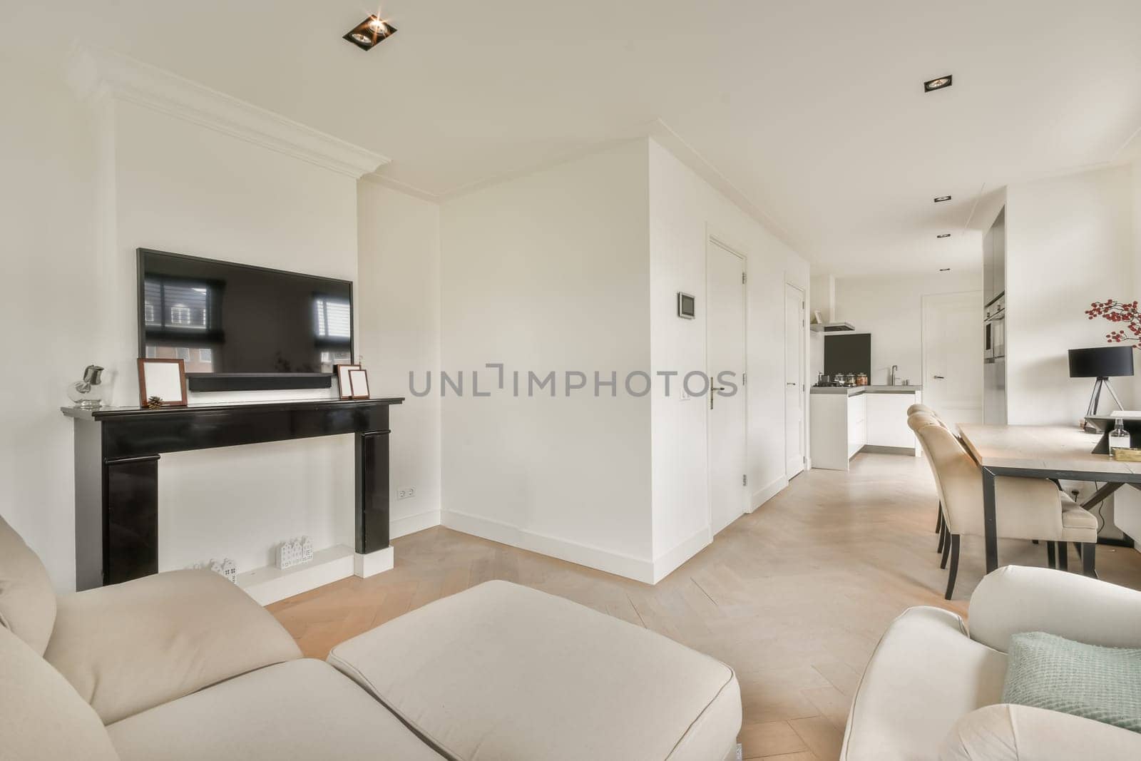 a living room with white furniture and a flat screen tv mounted on the wall above the fireplace in this apartment