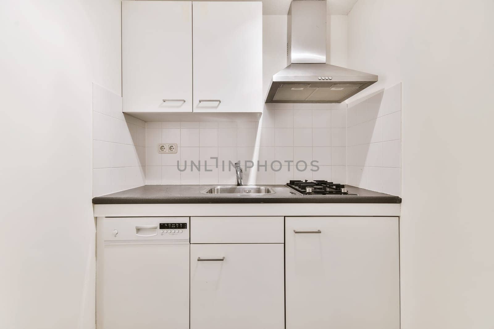 a small kitchen with white cabinets and black counter tops on the wall above it is a stove, sink and dishwasher