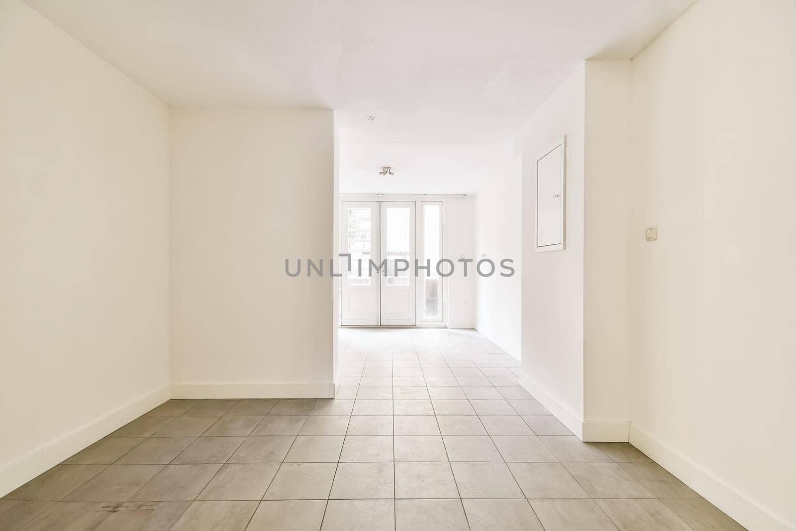 an empty room with white walls and wood flooring on the right, there is a door leading to another room