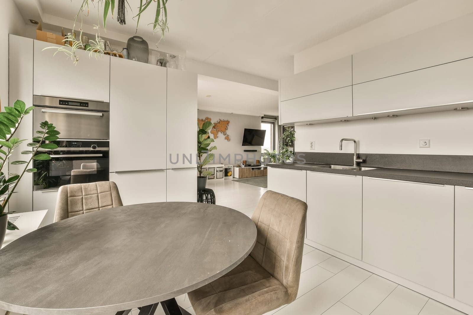a kitchen and dining area in a modern home with white cabinets, marble countertops, stainless appliances and a round table