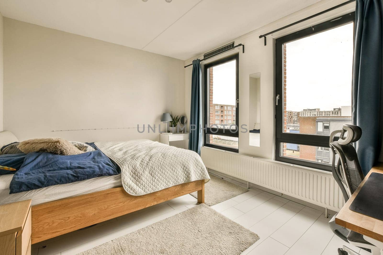 a bedroom with a bed, desk and window looking out onto the cityscapearron com logo on the wall