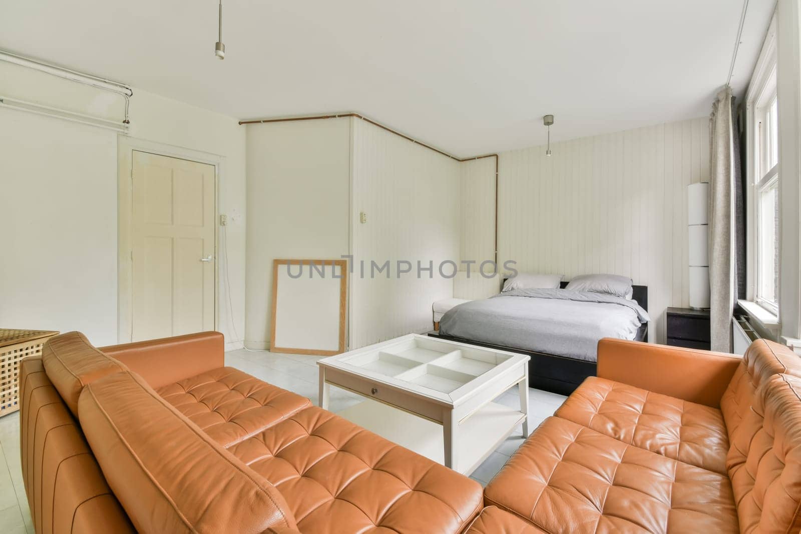a living room with orange leather couches and a white coffee table in the center of the room is a bed