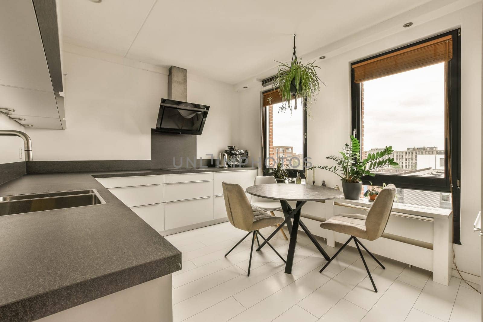 a kitchen and dining area in a modern apartment with white cabinets, black counter tops, and an open window overlooking the city