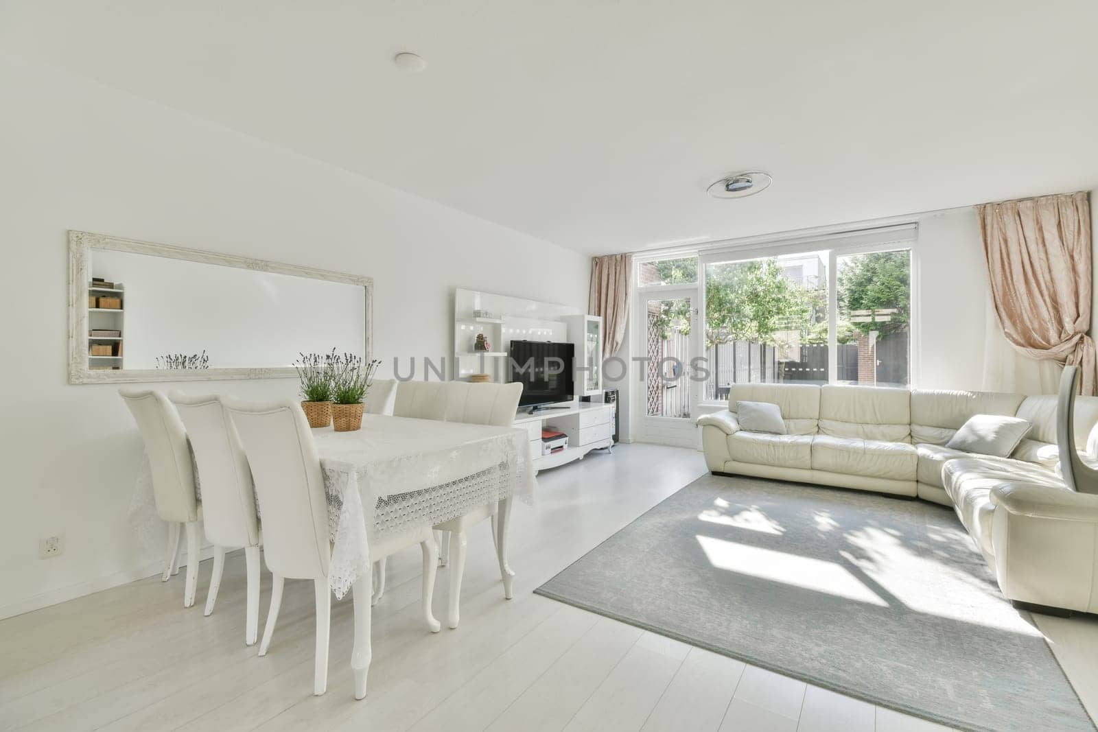 a living room with white furniture and an open door leading out to the patio, which has been used as a dining area