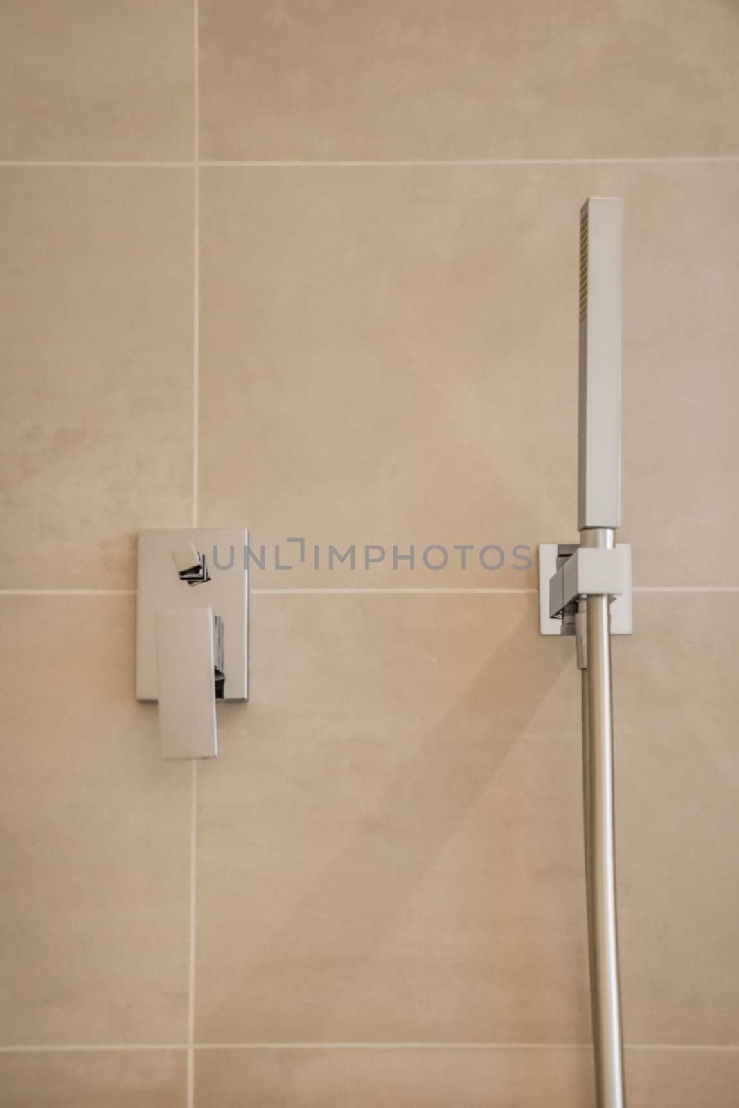 a shower head and hand rail in a tiled bathroom photo taken from the side, with focus to the wall stock photo