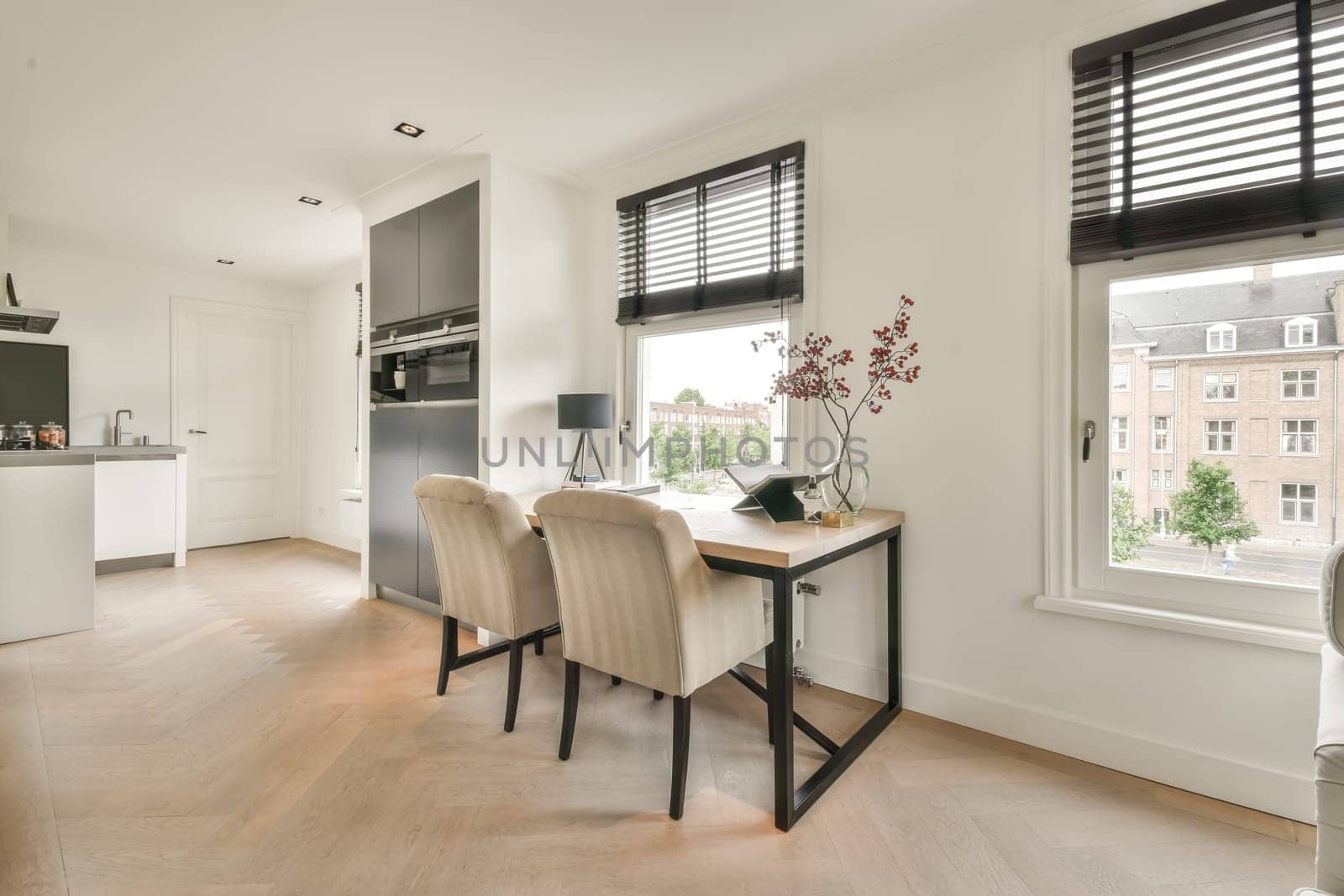 a kitchen and dining area in a modern apartment with white walls, hardwood flooring and large windows looking out onto the street