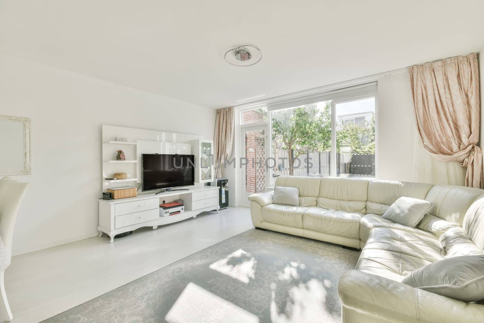 a living room with white furniture and pink drapes on the window is looking out onto an outdoor patio area