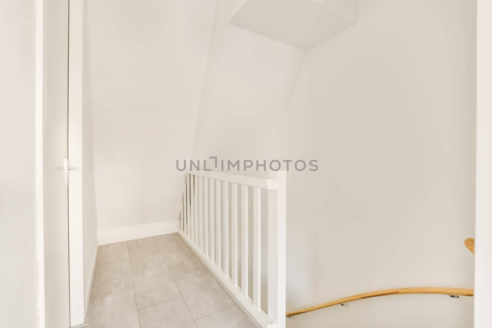 an empty room with white walls and wood railings on either side, there is a staircase leading up to the second floor
