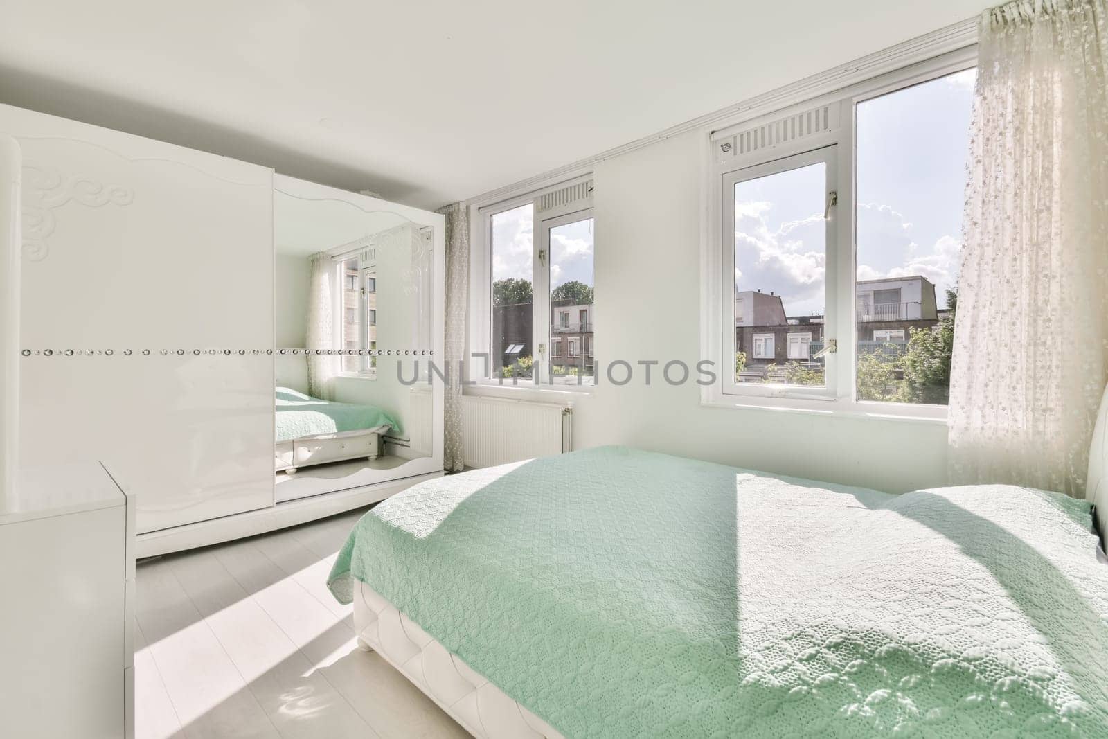a bedroom with white walls and green bedspremnveses on the bed in front of the window