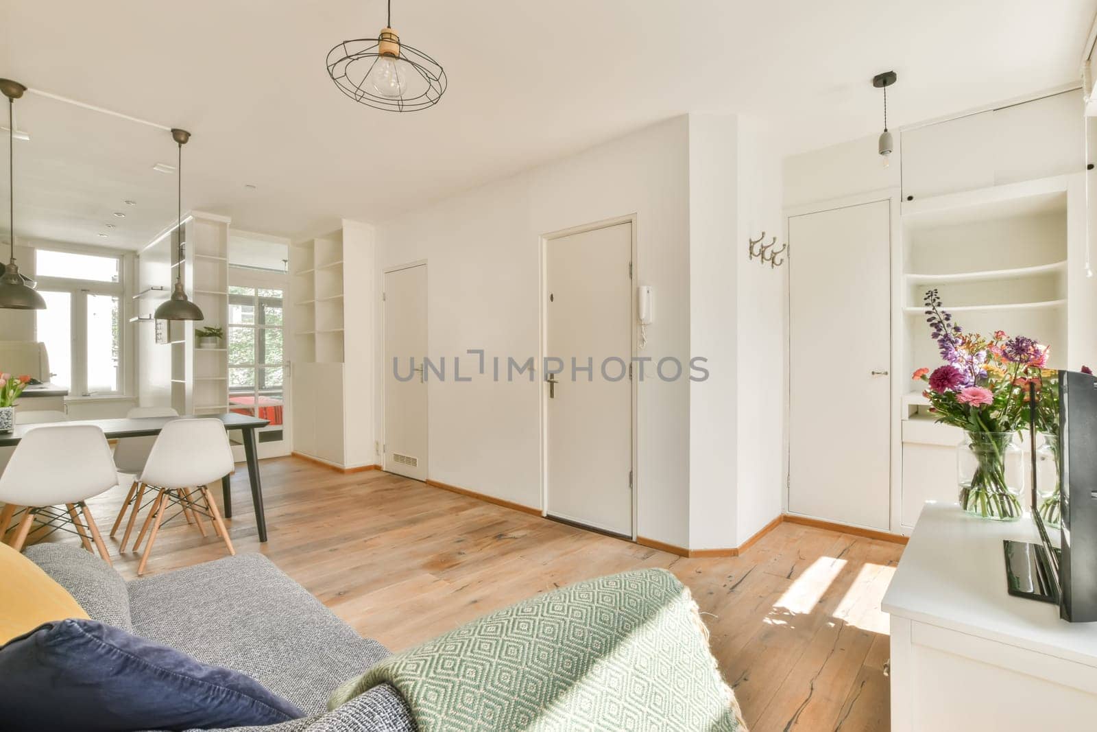 a living room with white walls and wood flooring in the center of the room is an open kitchen area