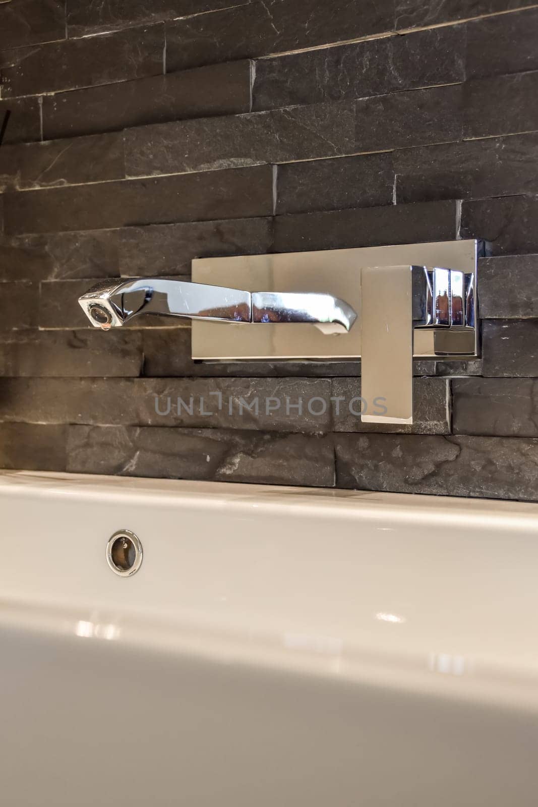 a bathroom sink with a mirror on the wall behind it is a white bathtub and black marble flooring
