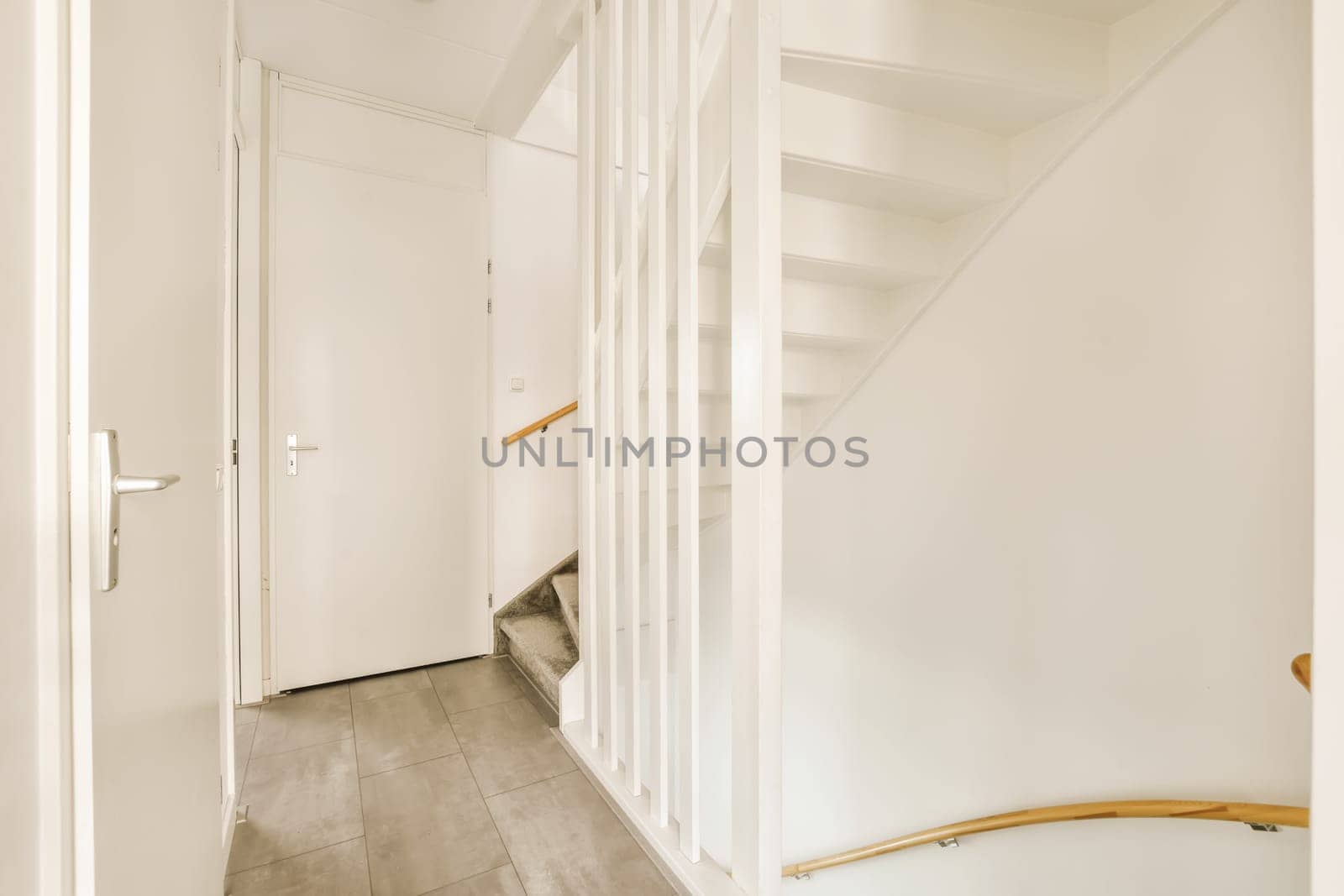a hallway with white walls and wooden stairs leading up to the second floor in an apartment or residential house interior
