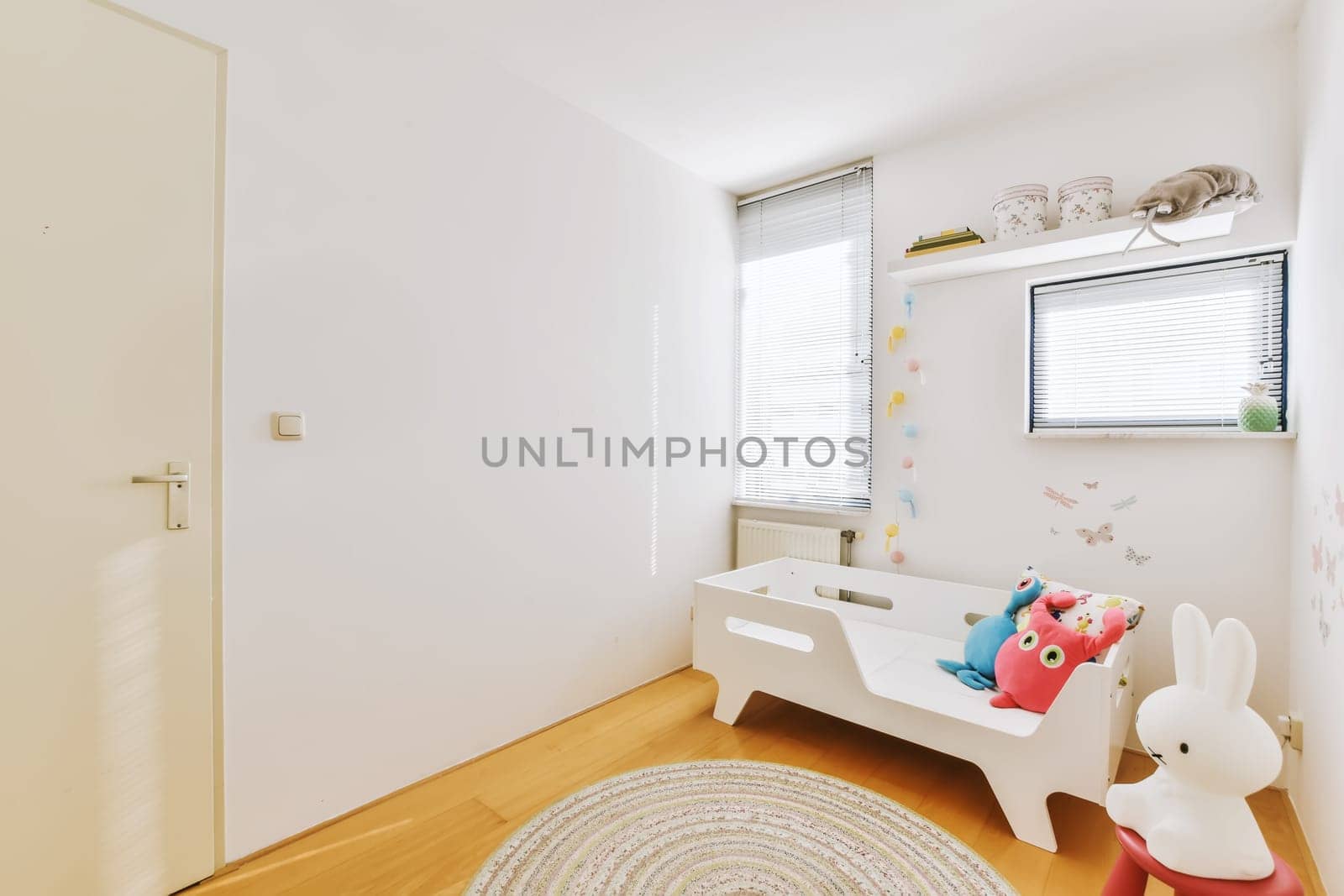 a child's room with white walls and wooden flooring the room is decorated in paste pink, blue and green tones