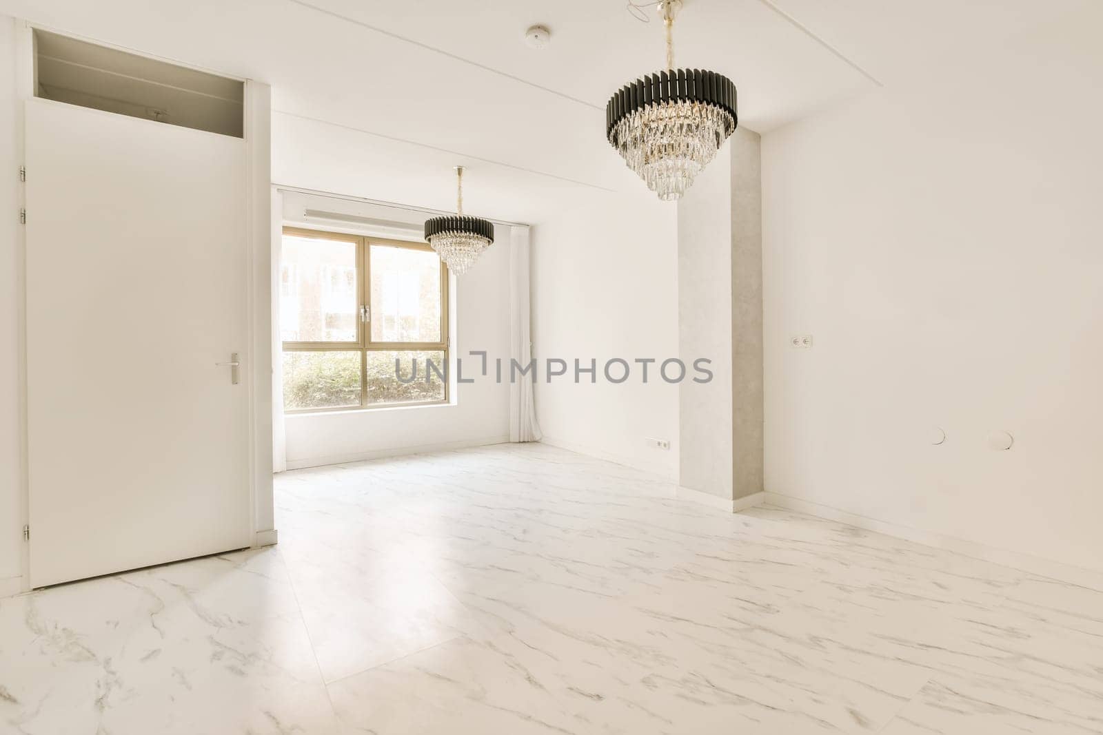 an empty room with white marble flooring and a chandel light hanging from the ceiling over the doorways