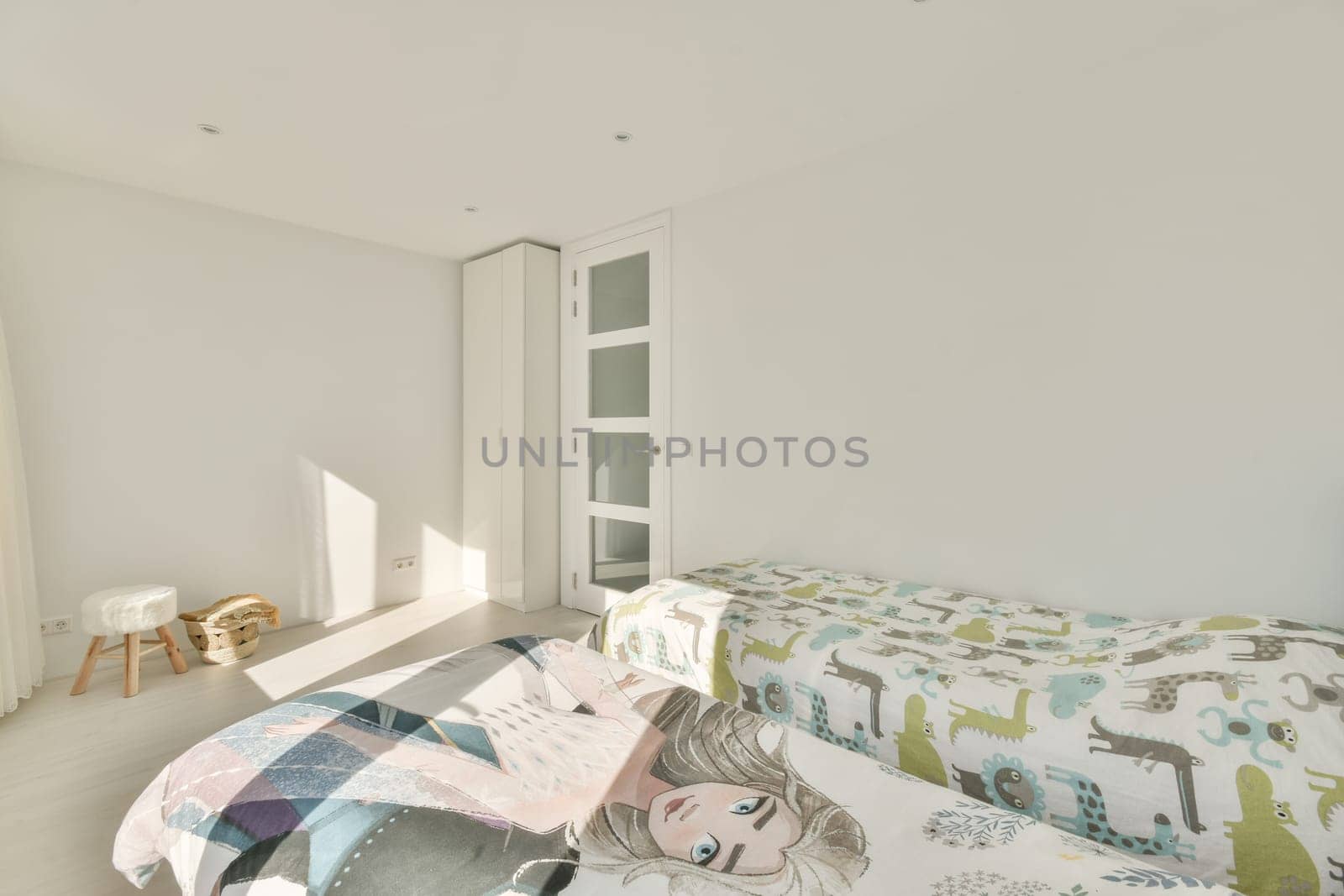 a bed in a room with white walls and wood flooring on the right side, there is an open door that leads to another room