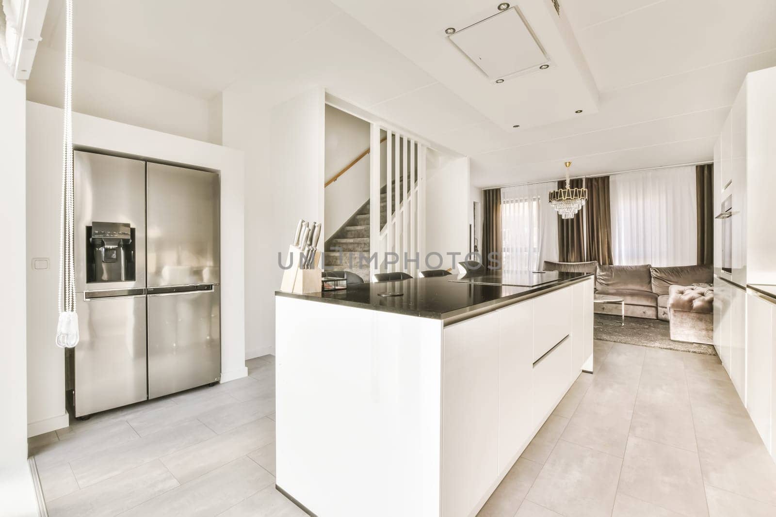 a modern kitchen with white cabinets and black countertops on the island in an open plan living room is also visible