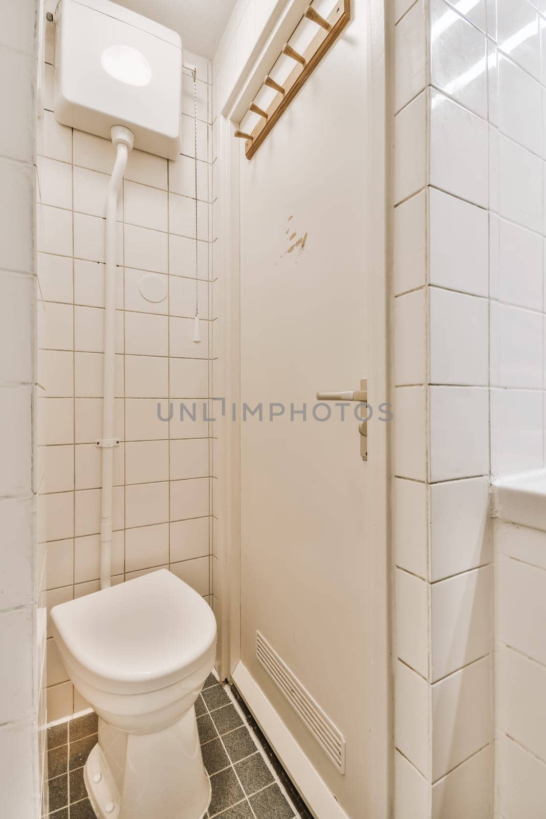 a white toilet in a small bathroom with tile flooring and wall tiles on the walls there is a mirror above it