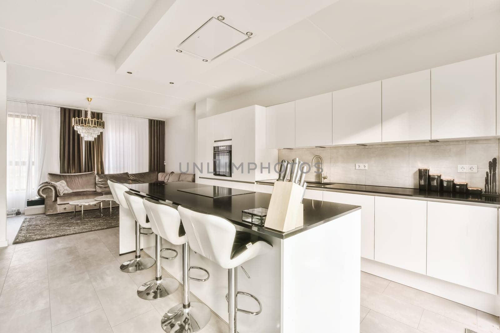 a kitchen and dining area in a modern style apartment with white cabinets, black counter tops and marble flooring