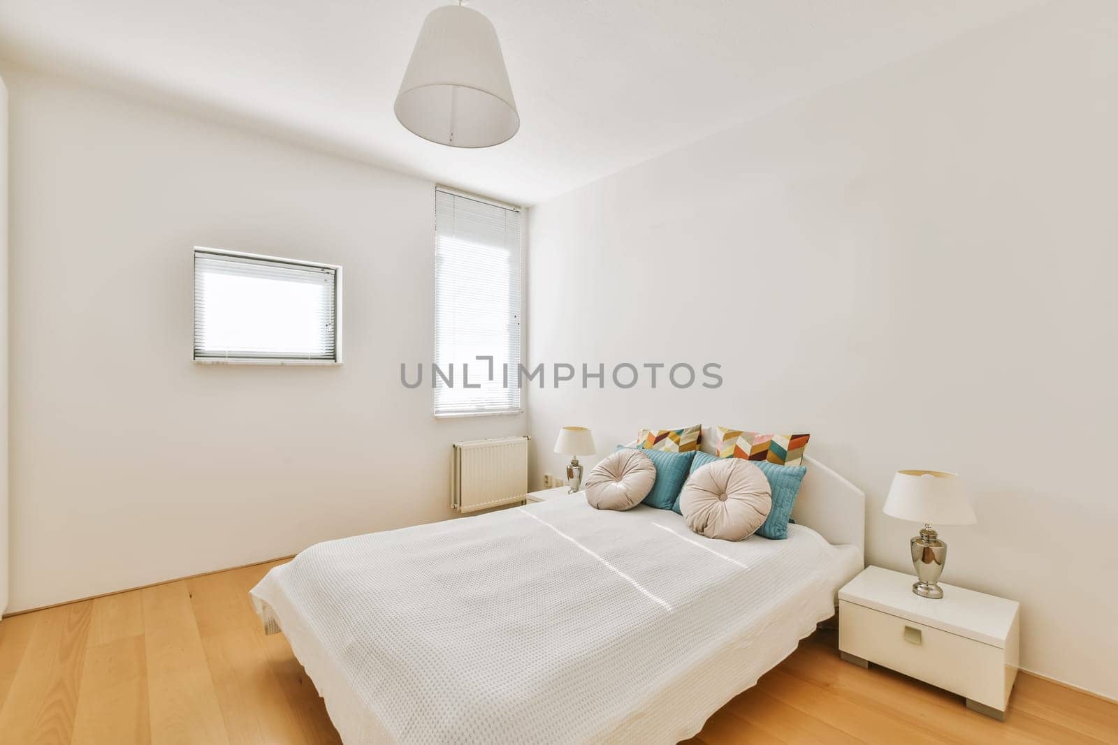 a bedroom with white walls and wood flooring the room has a bed, two nightstands and a window