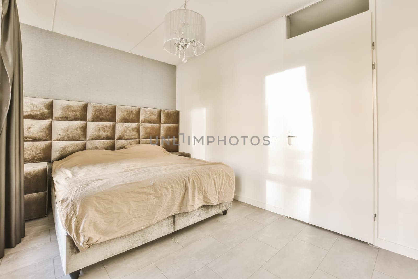 a bedroom with a bed and a chandel on the wall in front of the bed is an open door