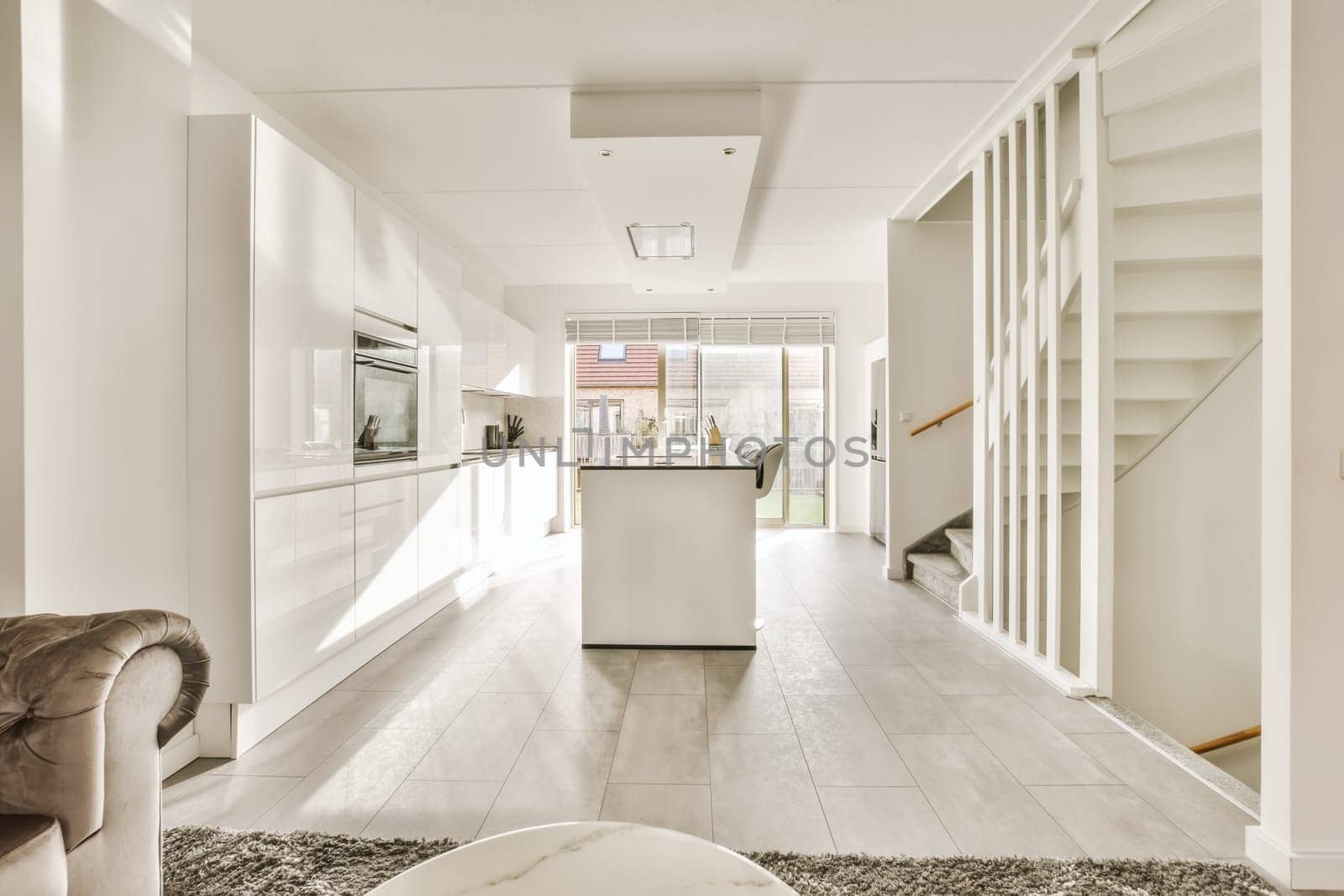 a kitchen and dining area in a house with white cabinets, marble flooring and an open staircase leading to the living room