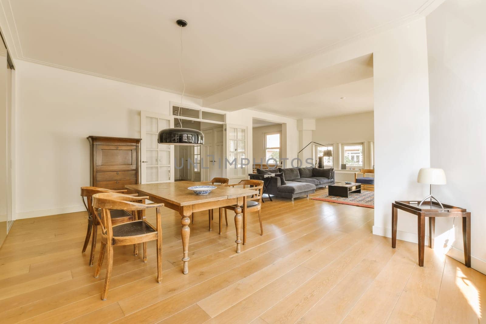 a living room with wood flooring and white walls, including a wooden dining table surrounded by two chairs in the room is empty