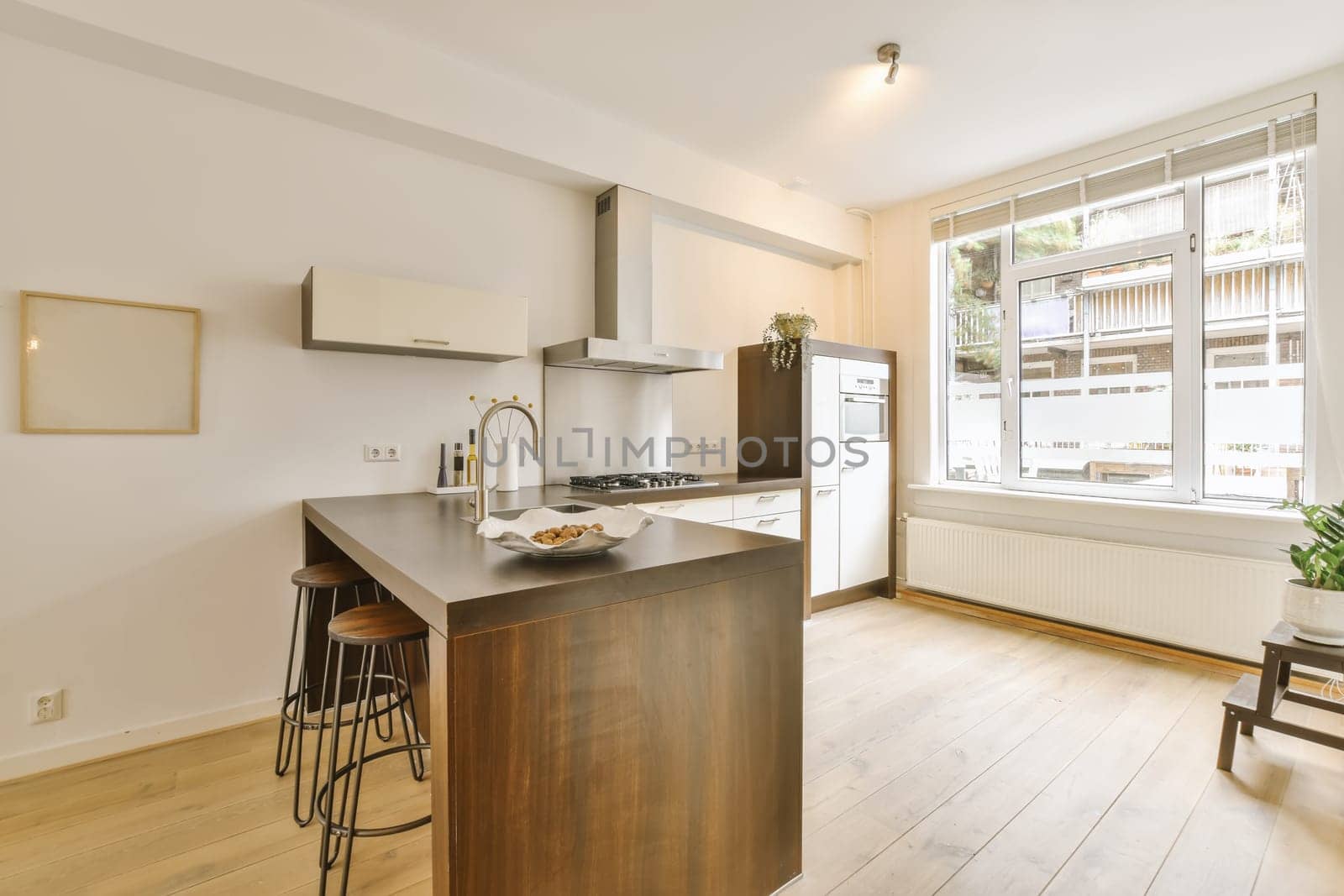 a kitchen and dining area in a house with white walls, hardwood flooring and large windows overlooking out onto the street