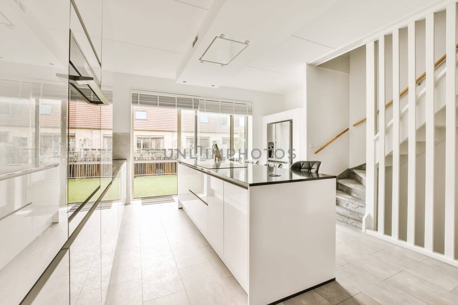 a modern kitchen with white cabinets and black counter tops in the center of the room, there is a glass door that leads to an outdoor patio