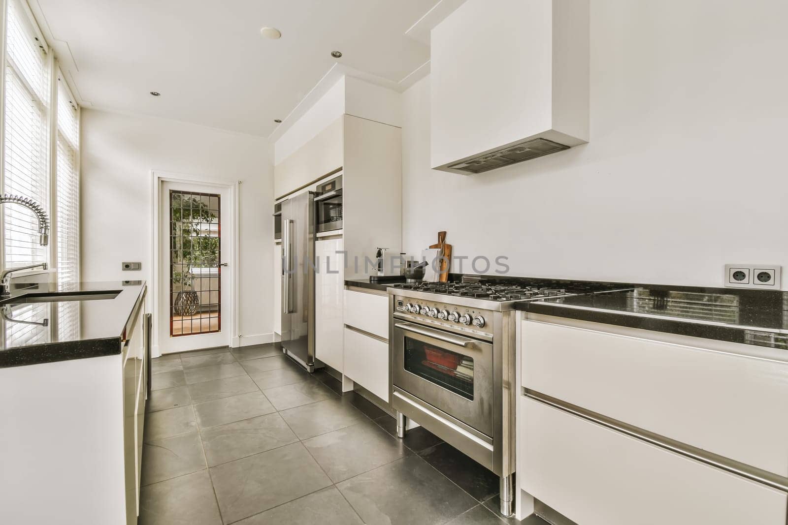 a modern kitchen with white cabinets and black countertops on the island in the center of the room is an open door that leads
