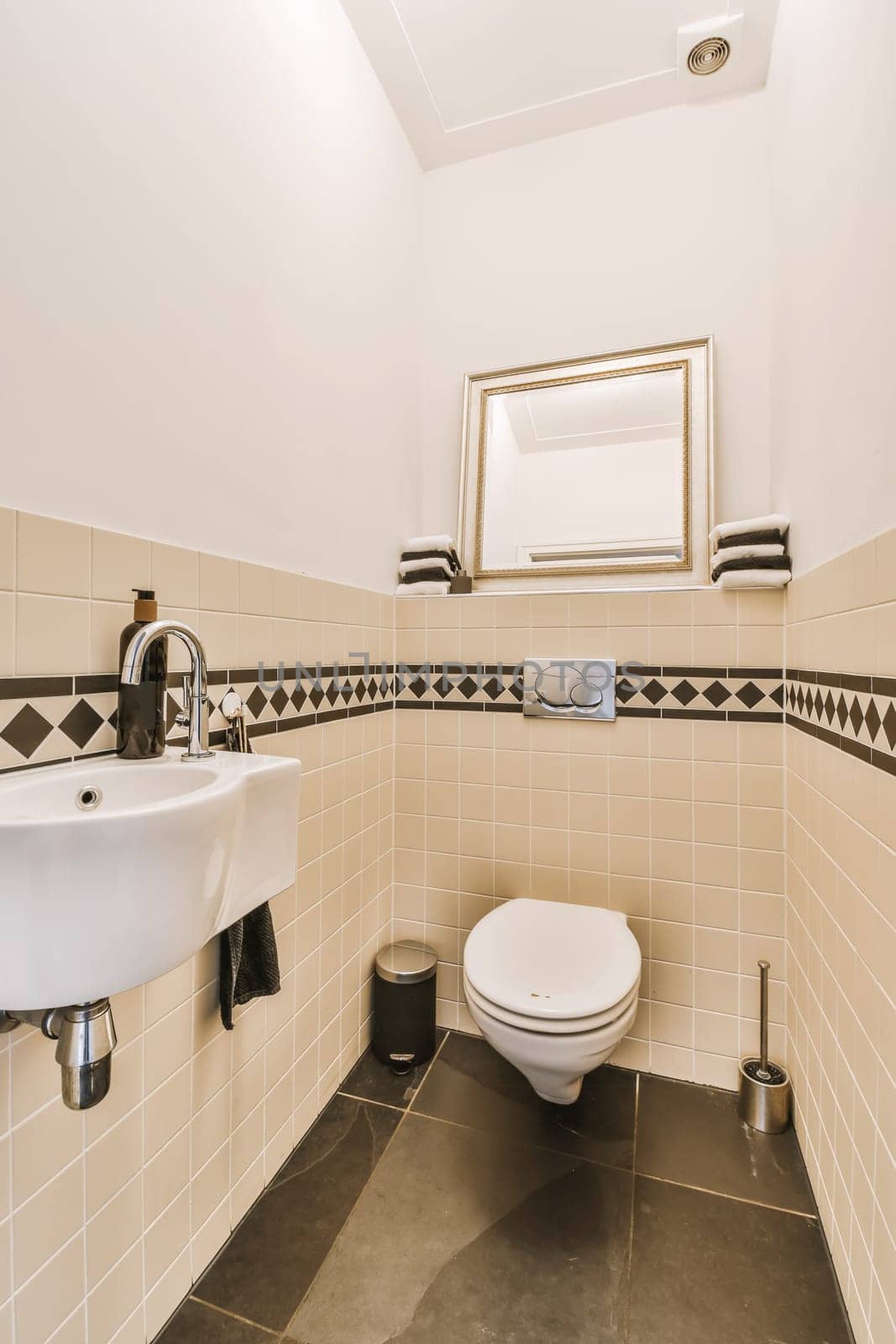 a bathroom with black and white tiles on the walls, sink, mirror and toilet in the room is very clean