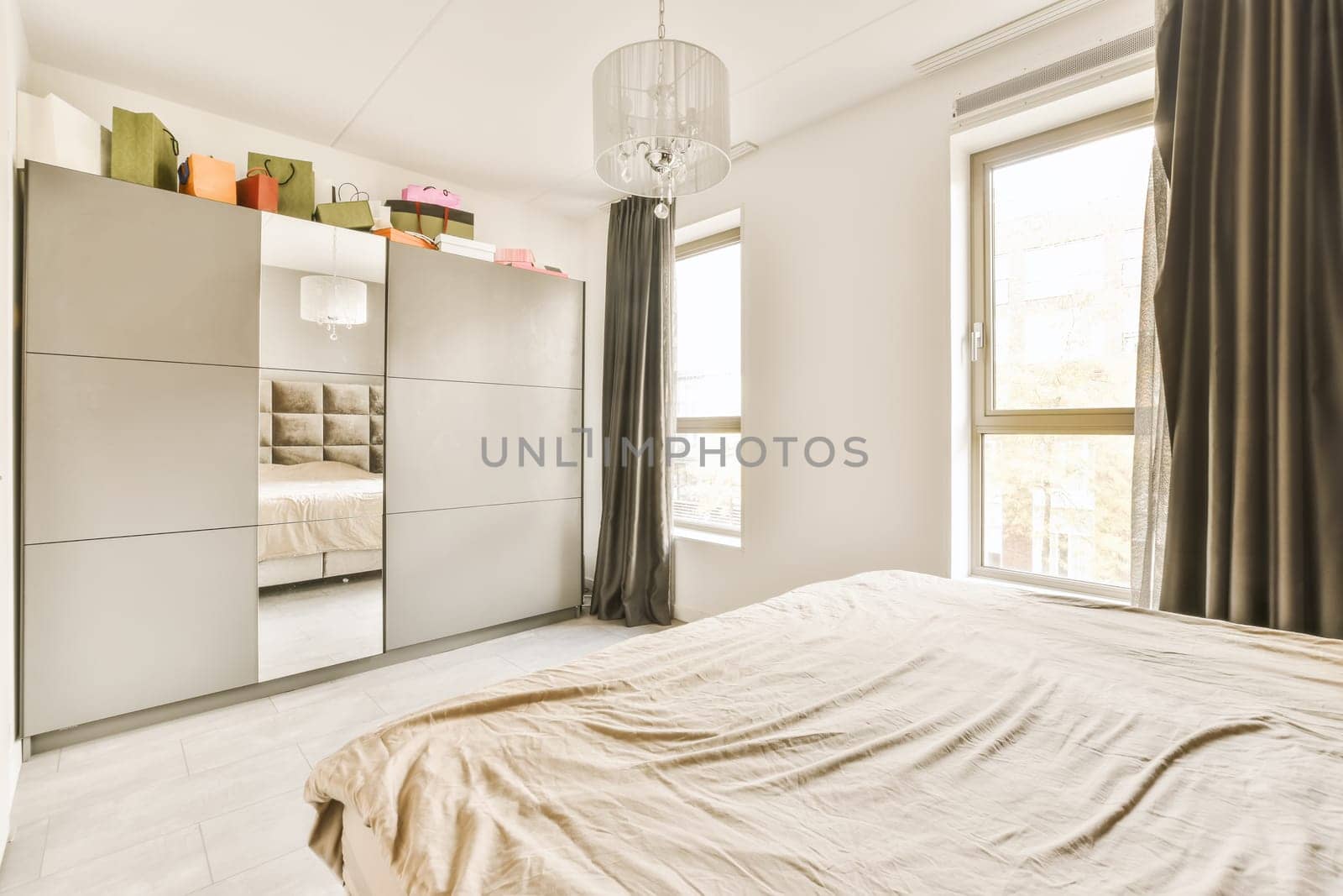 a bedroom with an unmade bed and wardrobes on the wall behind it is a large window that looks out onto the street