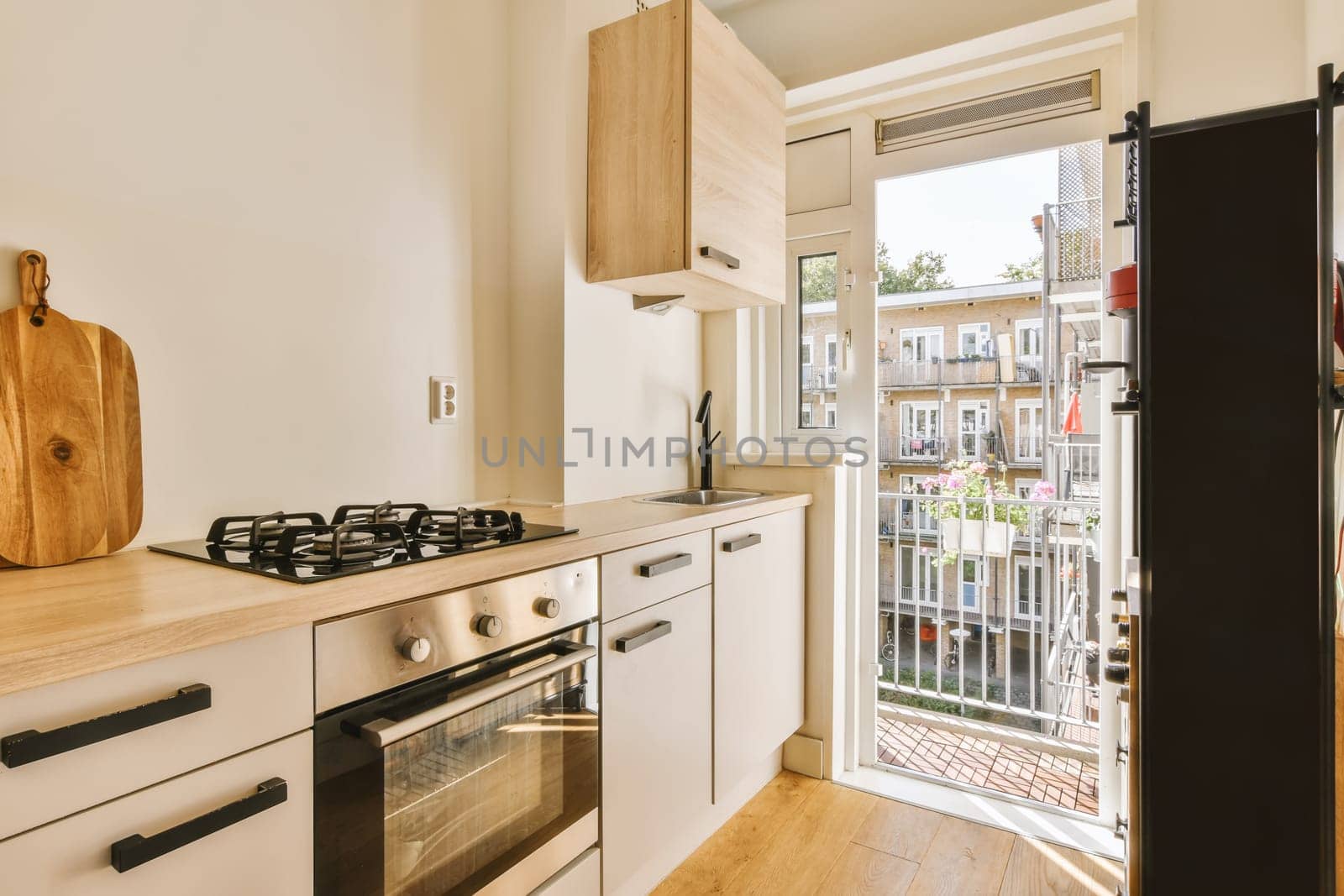 a kitchen with an open door leading to the patio area and outside view through the sliding glass door that leads out onto the balcony
