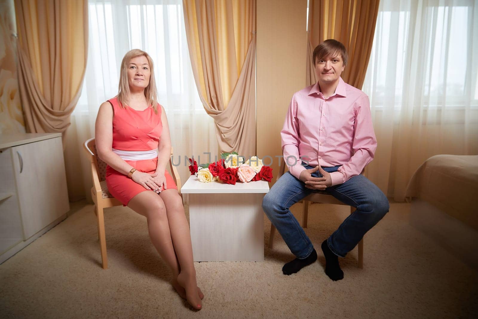 Couple poses together in a hotel room, surrounded by flowers, celebrating love and their special bond.