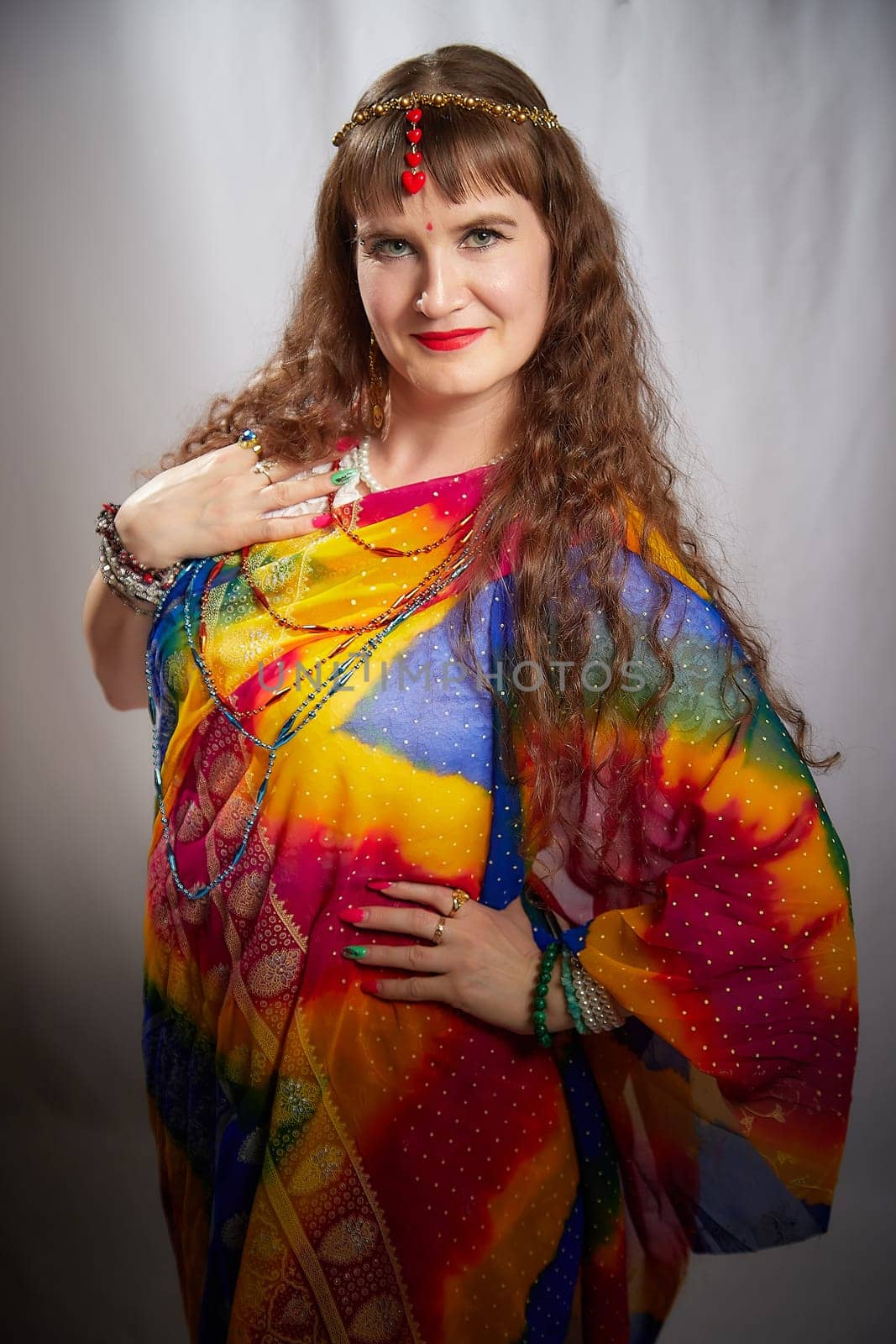 A middle-aged blonde woman showcases her beauty in a vibrant sari during a lifestyle photo shoot, posing with elegance and charm.