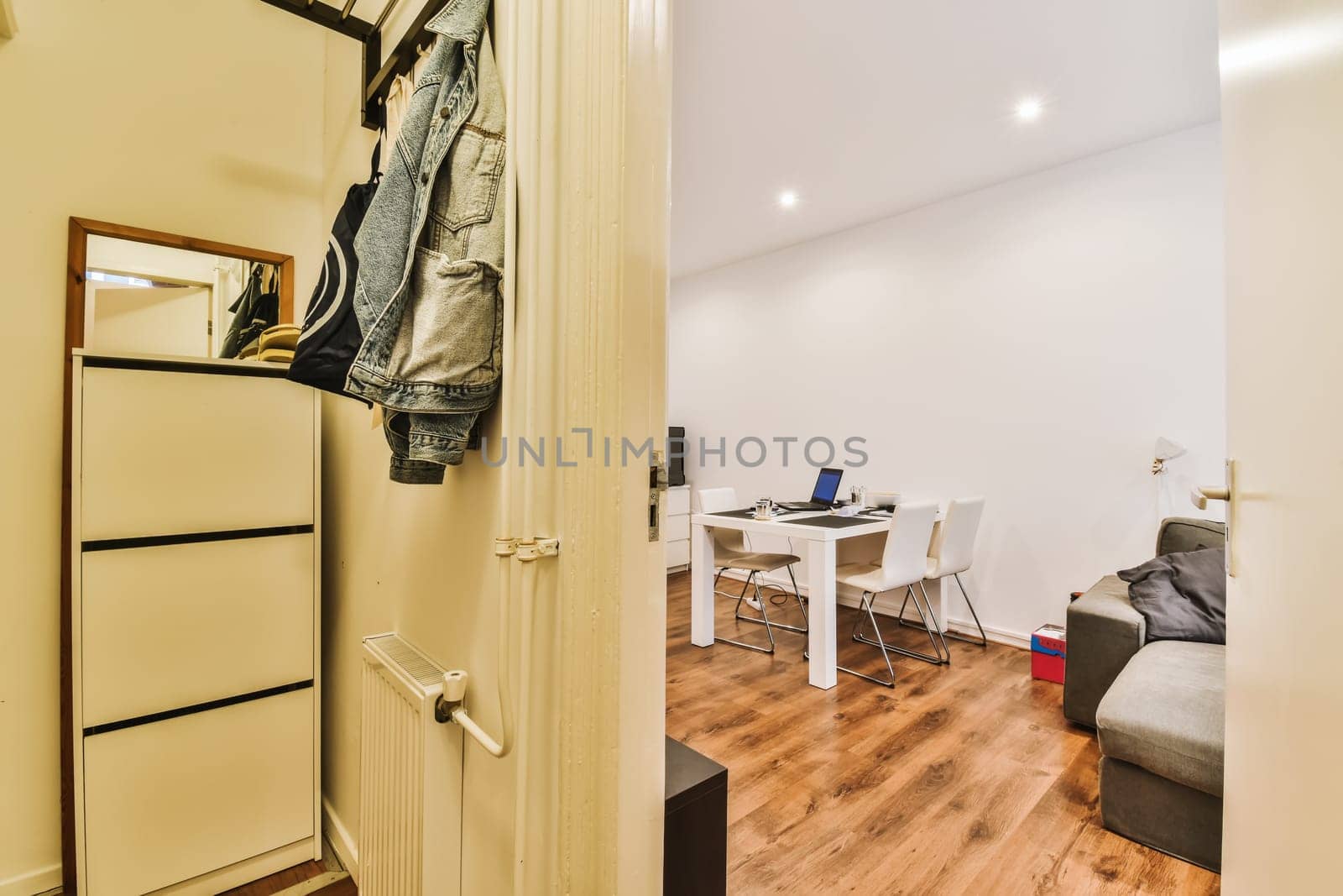 a living room with wood flooring and white walls there is a coat rack hanging on the wall next to the door