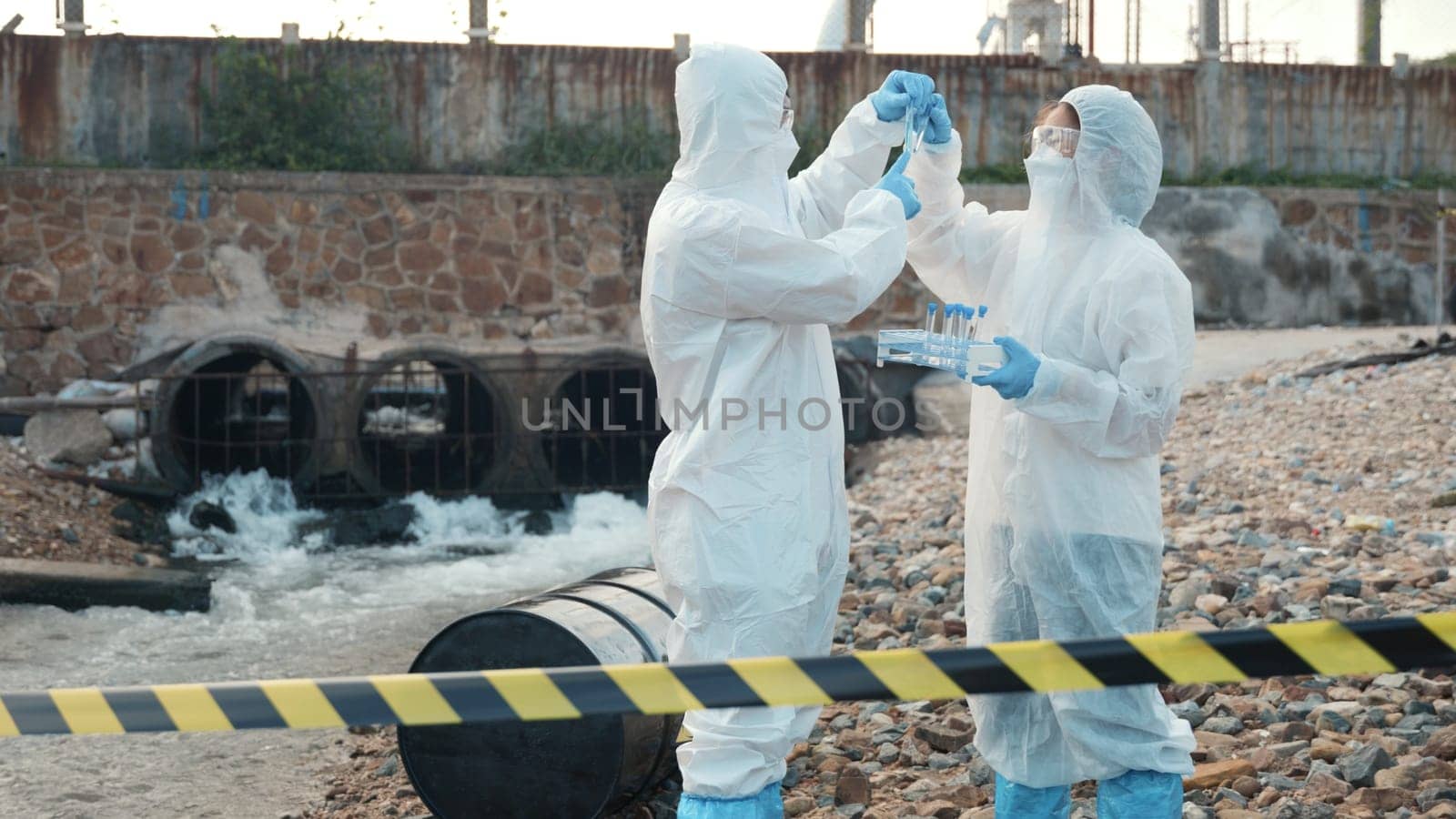 Ecologist sampling water from the river with test tube, Scientist or Biologist in a protective suit and protect mask collects sample of waste water from industrial for analyze, problem environment