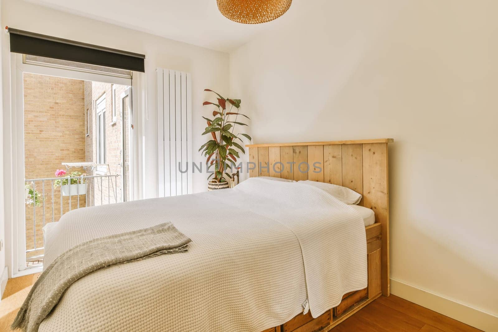 a bedroom with a bed, window and plant in the corner on the right side of the room is bright white walls