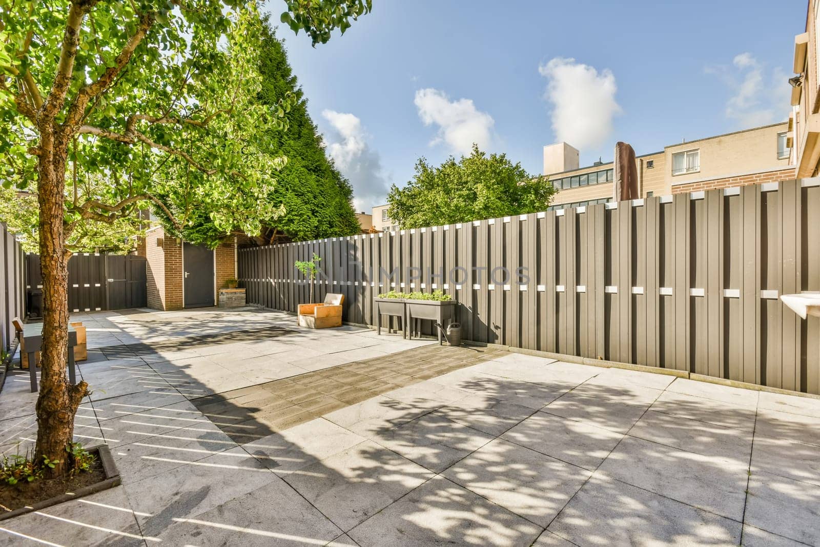 a fenced area with trees and buildings in the background on a sunny day at an urban townhome